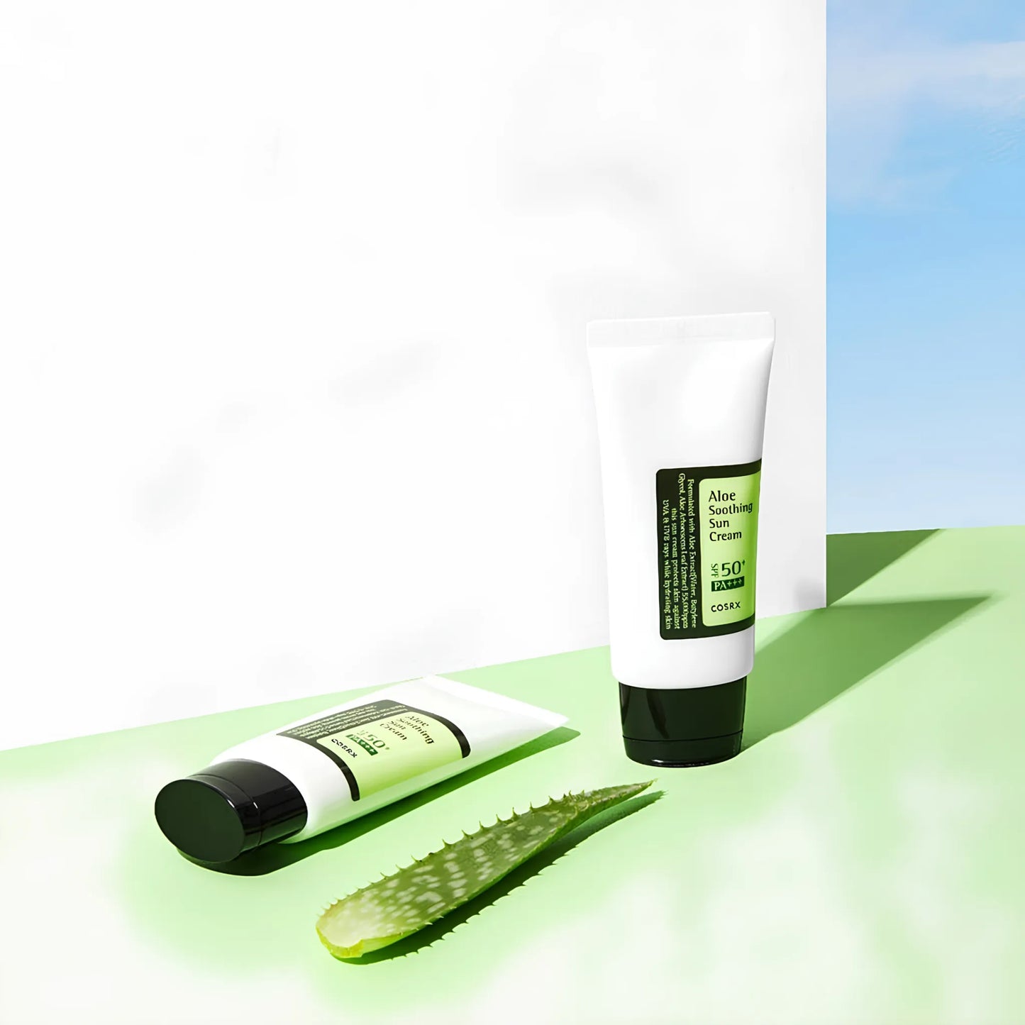 COSRX Aloe Soothing Sun Cream SPF50+/PA+++ 50ml, με δύο σωληνάρια του προϊόντος και μια φρέσκια αλόη να φαίνονται καθαρά, προσφέρει προστασία από τον ήλιο και ενυδάτωση.